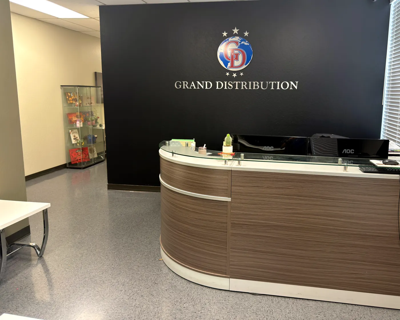 Reception desk in front of the GS Grand Distribution logo wall at the Union City office